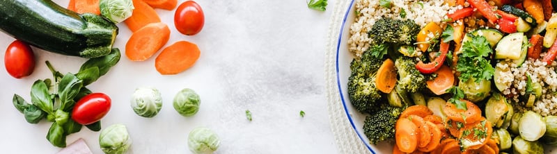 : Un platillo vegano a base de quinoa, brócoli, zanahoria y pimentón. A su izquierda otros vegetales.