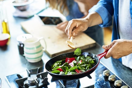 man frying vegetables in a pan